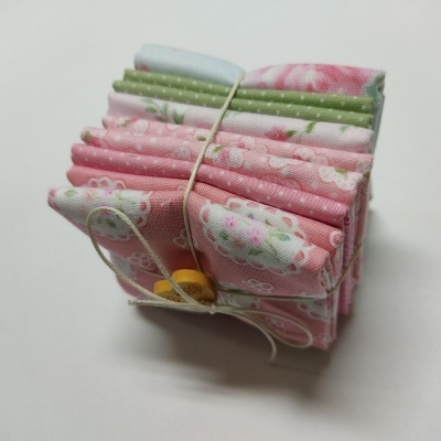 Pacote de tecidos rosa e verde com padrões florais amarrados com fio e botões