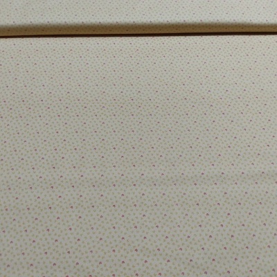 Tecido bege claro com pequenos pontos cor de rosa em rolo aberto