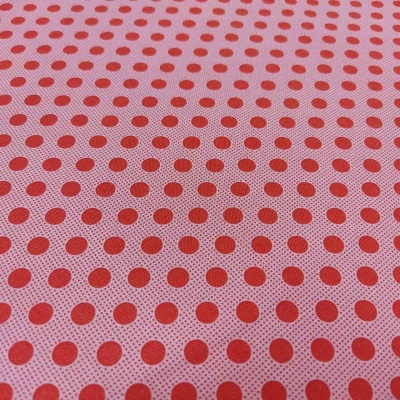Tecido cor-de-rosa com bolinhas vermelhas distribuídas em padrão uniforme