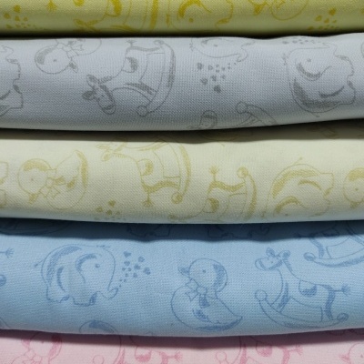 Tecidos infantis em várias cores com padrões de animais e brinquedos.