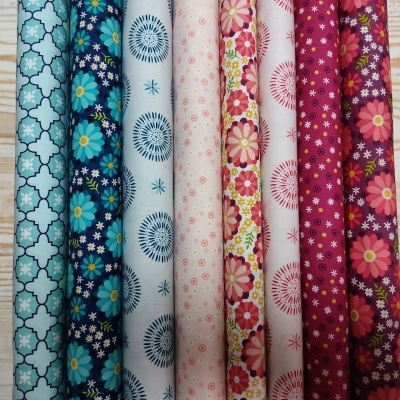 Sete rolos de tecido com padrões florais e geométricos em várias cores