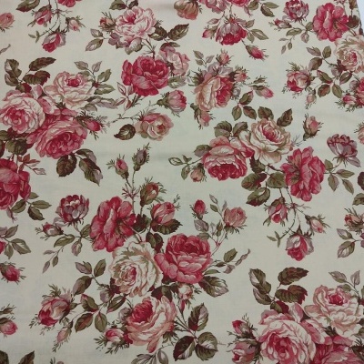 Tecido estampado com padrão floral em vermelho, rosa e verde sobre fundo bege