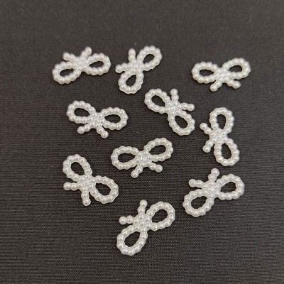 Objetos decorativos em forma de laço feitos de pérolas brancas sobre fundo preto