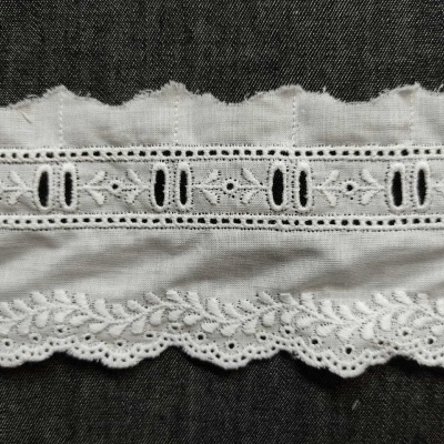 Tecido branco com duas rendas decorativas em fundo escuro