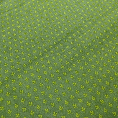 tecido verde com pequenos motivos florais amarelos repetidos