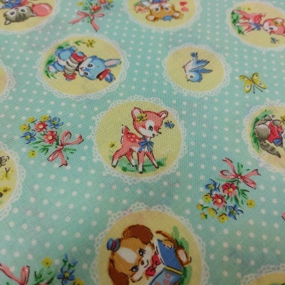 Tecido azul claro com bolinhas brancas e desenhos de animais e flores em círculos
