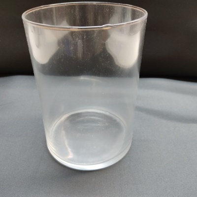 Copo de vidro transparente cilíndrico sobre superfície cinza