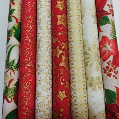 Rolos de tecido com padrões natalinos coloridos em vermelho, branco e dourado.