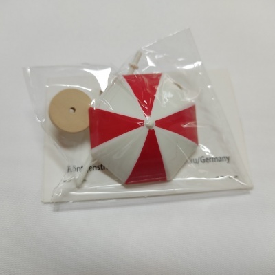 Guarda-sol vermelho e branco com base de madeira em embalagem de plástico