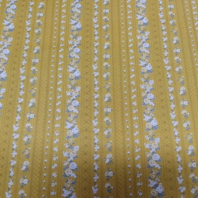 Tecido amarelo mostarda com flores azuis e brancas em riscas verticais