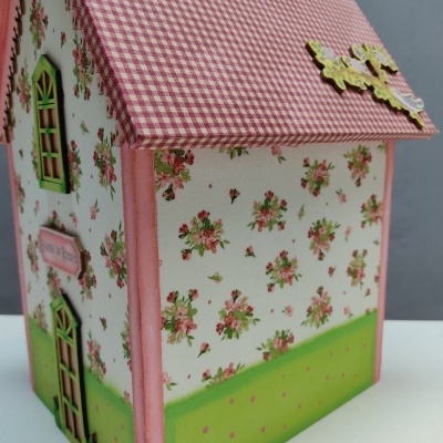 Caixa decorativa em forma de casa com padrão floral e tecto xadrez