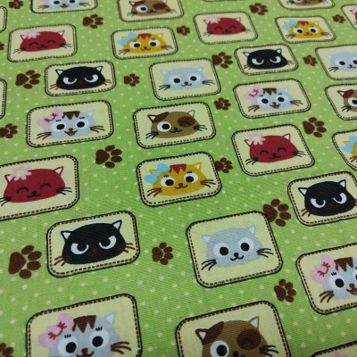 Tecido verde com estampado de gatos coloridos e pegadas de patas