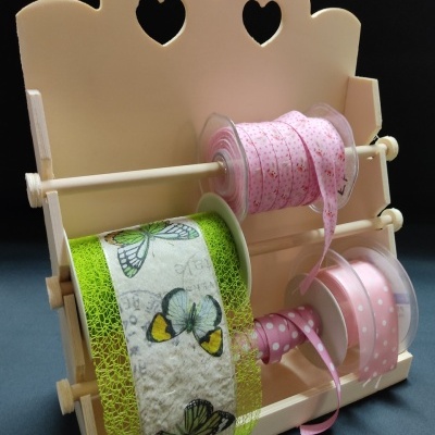 Expositor de madeira com rolos de fitas decorativas em verde e rosa