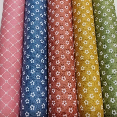 Cinco rolos de tecido coloridos com padrões pequenos florais e geométricos.