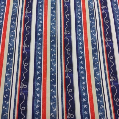 Tecido com padrão náutico em riscas verticais azul, vermelho, branco e bege com âncoras, estrelas e cordas