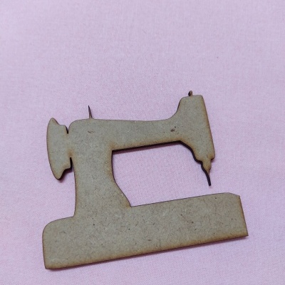 Figura decorativa de máquina de costura em madeira sobre tecido rosa