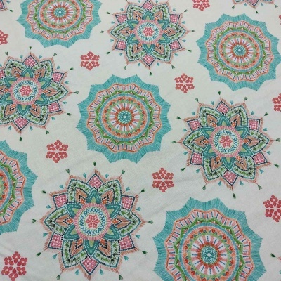 Tecido com padrão de mandalas coloridas e pequenos elementos florais