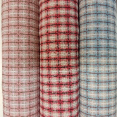 Três rolos de tecido xadrez em tons bege, vermelho e azul