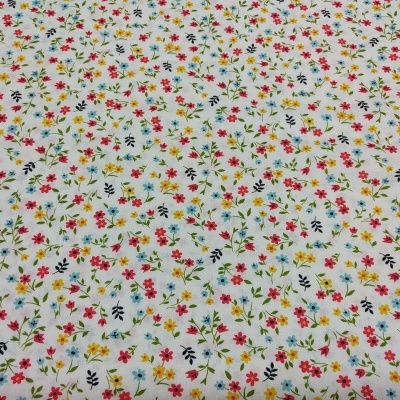 tecido branco com padrão de pequenas flores coloridas e folhas pretas