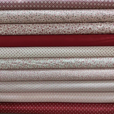 Tecidos vermelhos e brancos com padrões florais, bolinhas e geométricos empilhados.