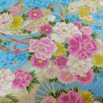 Tecido azul claro com padrão floral em rosa, branco e amarelo com detalhes dourados.