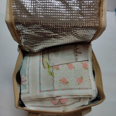 Bolsa térmica aberta a mostrar toalhas floridas de cores suaves