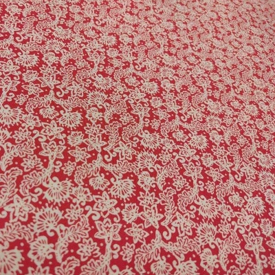 Tecido vermelho com padrão floral branco detalhado