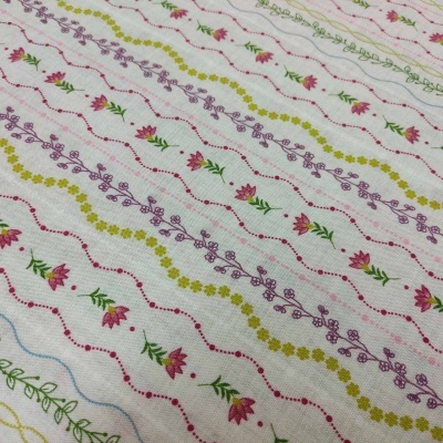 Tecido branco com flores e linhas coloridas onduladas e pontilhadas.