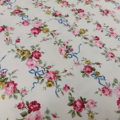 tecido branco com padrão floral de rosas vermelhas, rosas e amarelas e fitas azuis