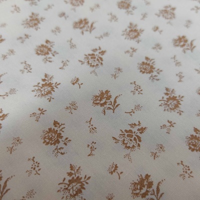 Tecido branco com padrão de pequenas flores castanhas