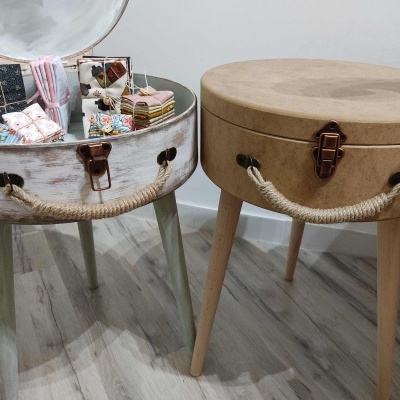 Mesas feitas de tambores de madeira com alças de corda, uma aberta com caixas dentro e outra fechada.