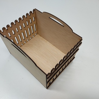 Caixa de madeira clara retangular com laterais vazadas e entalhes decorativos, vista superior