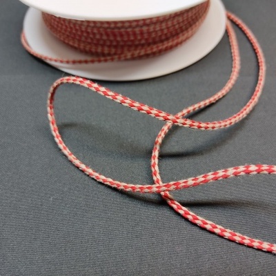 Fita têxtil vermelha e branca desenrolada sobre superfície preta