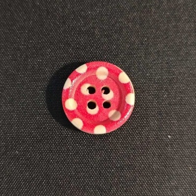 Botão vermelho com bolinhas brancas sobre tecido preto