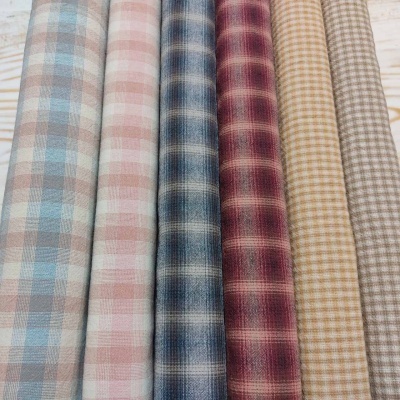 Rolos de tecido quadriculado em várias cores pastel sobre madeira