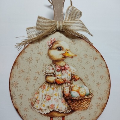 Tabua de madeira decorativa com pato vestido e cesta de ovos coloridos