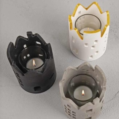 Três castiçais de vela em cerâmica com formato de castelo e vela acesa