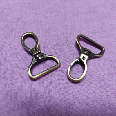 Dois mosquetões metálicos bronze sobre tecido lilás