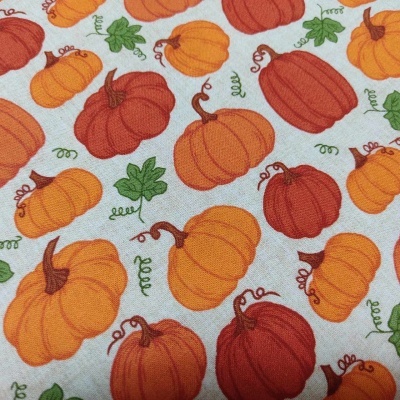 Tecido com padrão de abóboras laranja e amarelas e folhas verdes