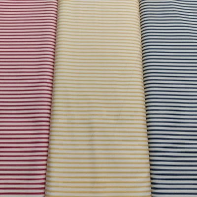 Três tecidos de riscas finas cores vermelho, amarelo e azul lado a lado