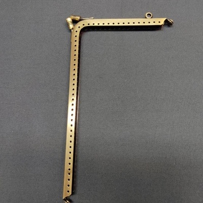 Peça metálica dourada em ângulo com furos sobre superfície cinza