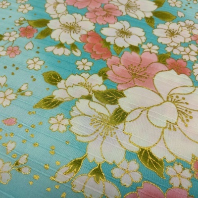 tecido azul claro com flores brancas, rosas e detalhes dourados, padrão floral