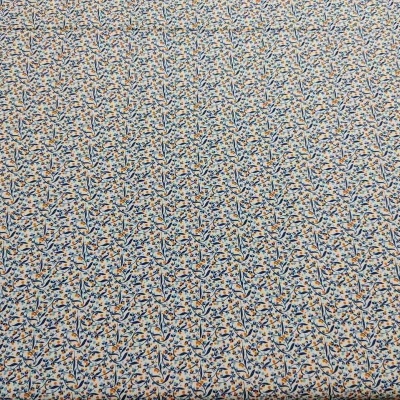 Tecido creme com padrão de folhas azuis, laranjas e verdes