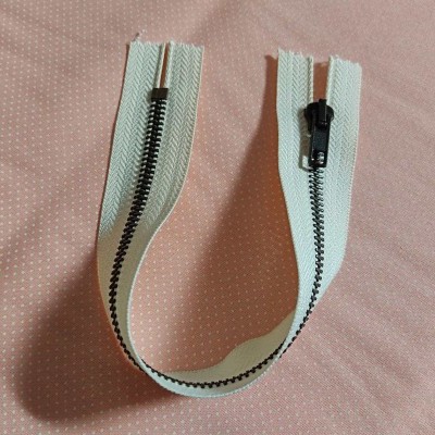 Fecho éclair branco com dentes pretos sobre tecido rosa com pontos brancos