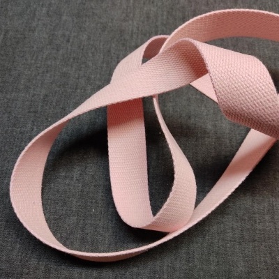 Fita rosa de tecido entrelaçada sobre tecido cinzento