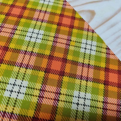 tecido xadrez colorido em verde, laranja, vermelho e branco sobre madeira clara