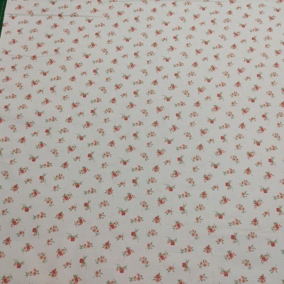 Tecido branco com pequenas flores vermelhas e verdes repetidas