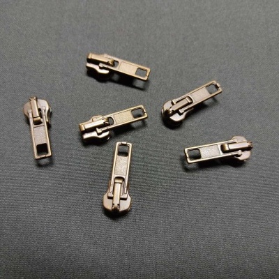 Seis carripanes metálicos em bronze sobre tecido cinzento