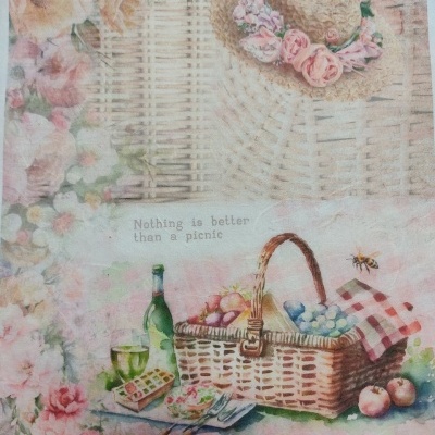 Cesta de piquenique com frutas, bebida e chapéu de palha decorado com flores, em fundo floral.