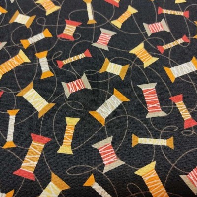 Tecido preto com carretéis de linha coloridos estampados